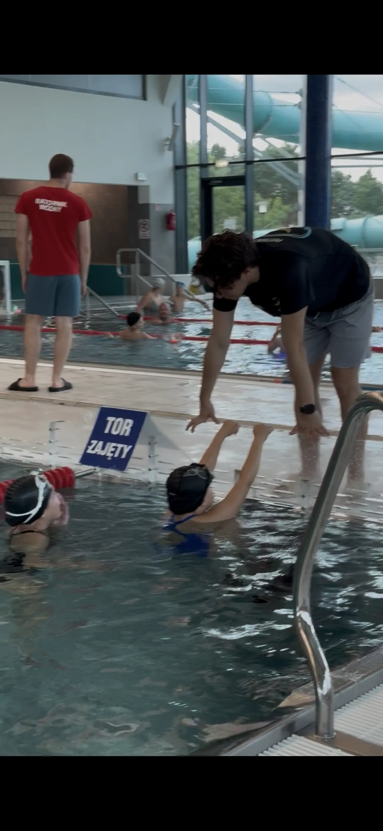Instruktor Bonito Swim prowadzi ćwiczenie z dwiema dziewczynkami przy brzegu basenu